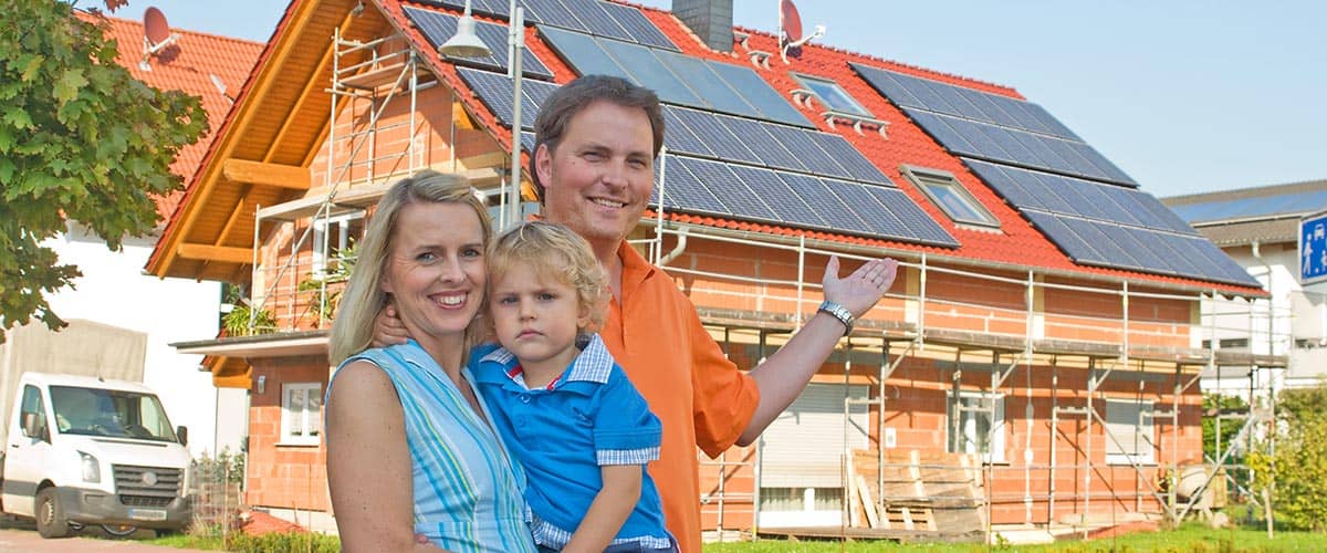 Erneuerbare Energie: Familie vor Neubau mit Photovoltaikanlage
